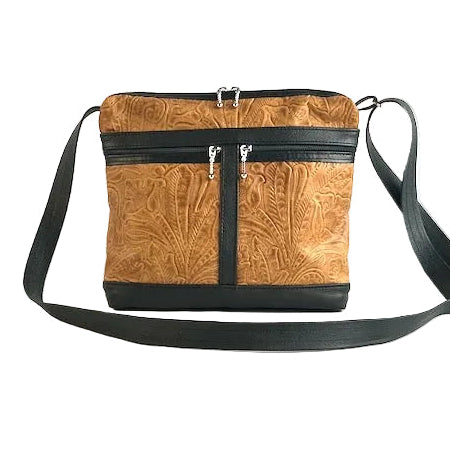 lightweight tan floral tooled leather crossbody bag with black accents on a white background